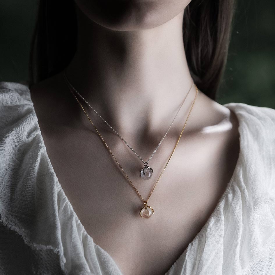 Model wearing layered gold and silver crystal ball necklaces