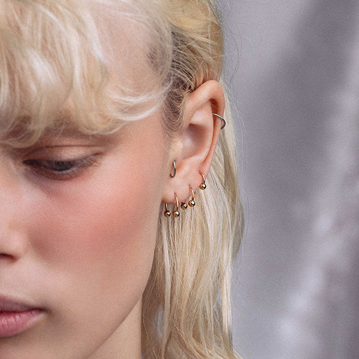 CLEO. Circular Titanium Barbell Ring - Gold model wearing the gold titanium ring as ear piercings