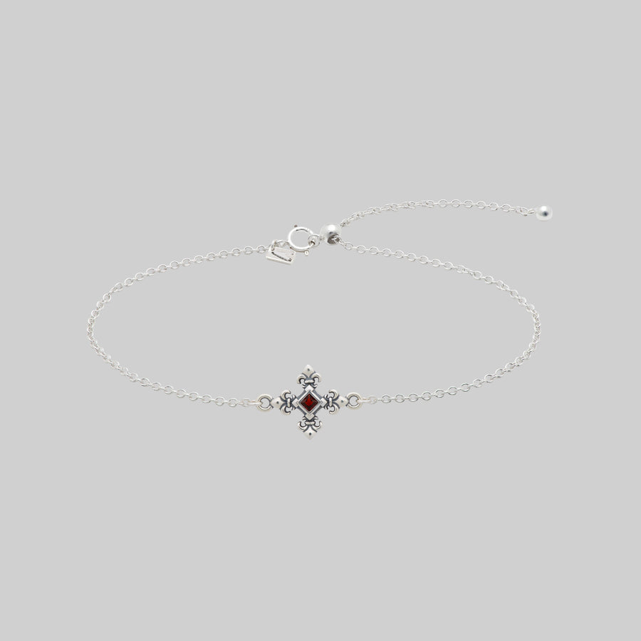 Silver dainty bracelet with a garnet stone and decorative clasp