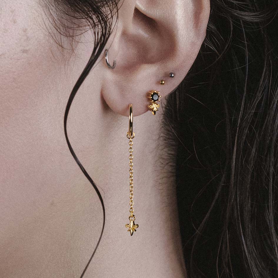 Model wearing Fiora gold heraldic lily stud and drop hoop earrings