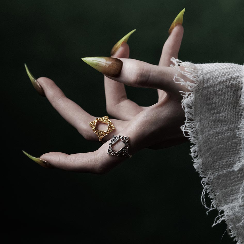 Model wearing gold and silver ornate frame rings