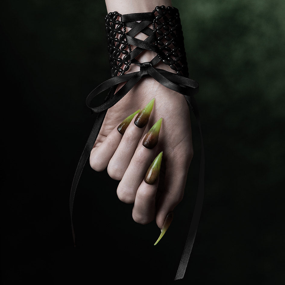 Model wearing black beaded corset cuff, ribbon lacing at back of wrist