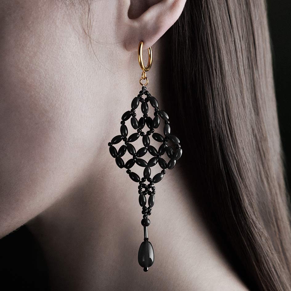 Model wearing black beaded chandelier drop earring on gold hoop