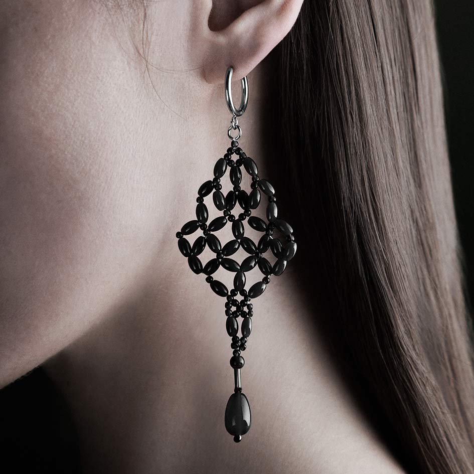 Model wearing black beaded chandelier drop earring on silver hoop