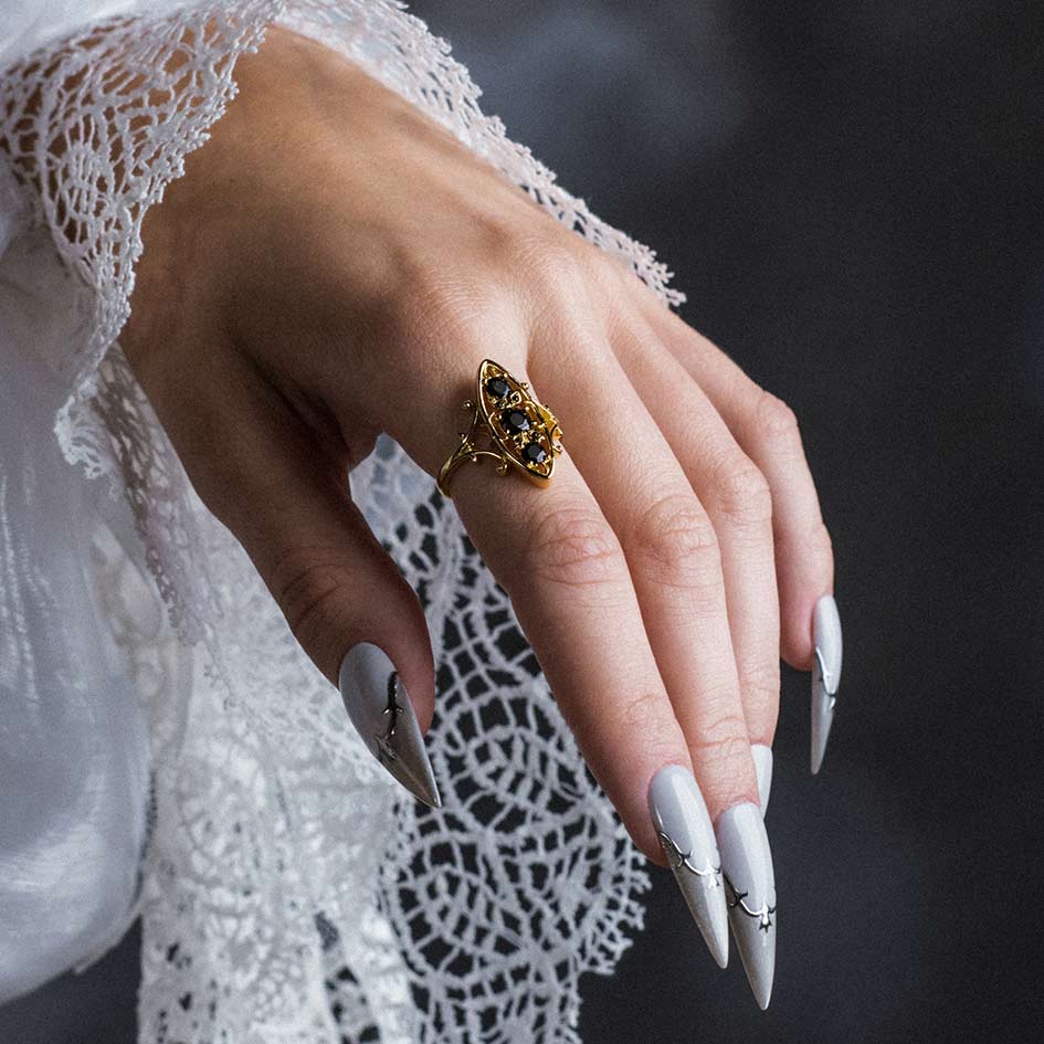Model wearing Heloise gold heraldic lily black onyx ring