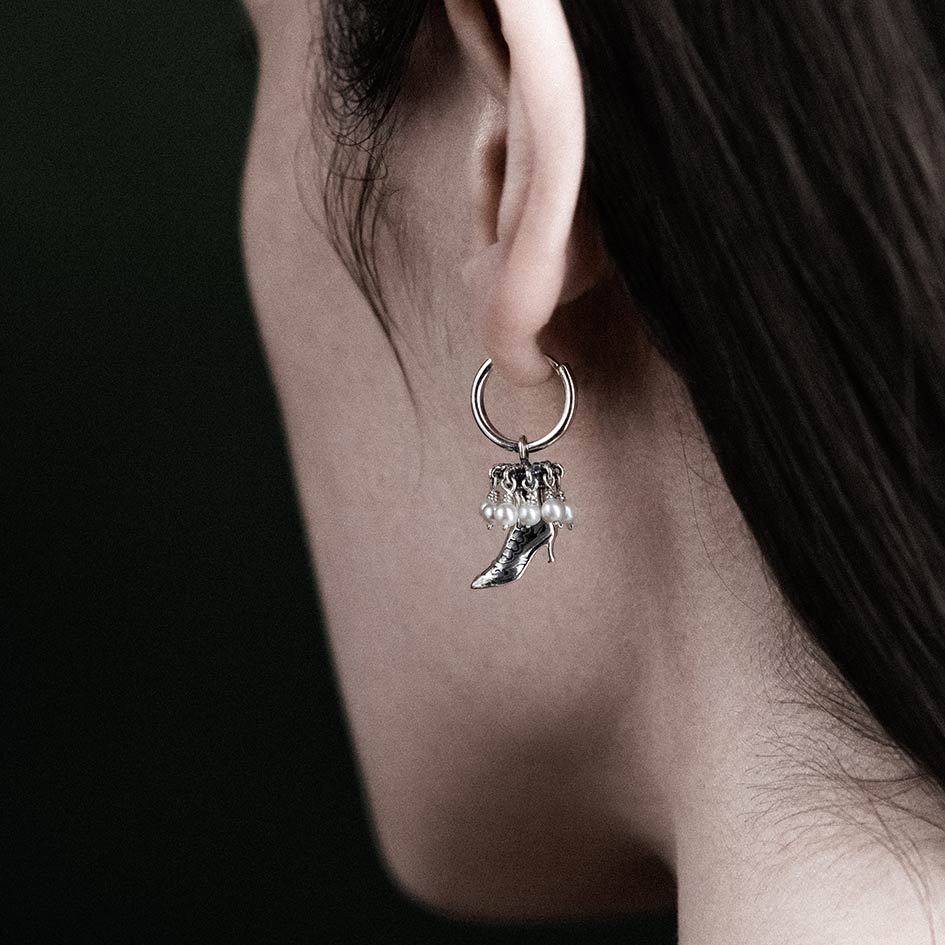 Silver hoop earring with a dangling silver boot charm adorned with small white pearls