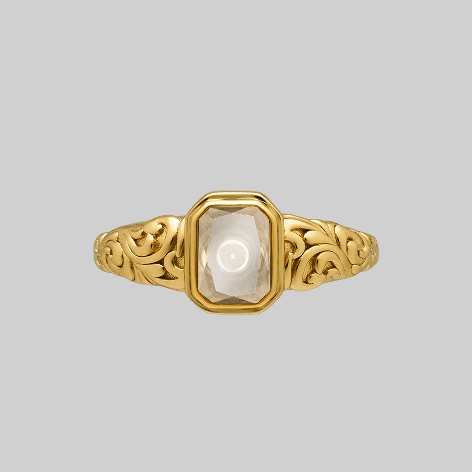 Gold cremation ring with an emerald cut Clear Quartz window set between scroll engraved shoulders