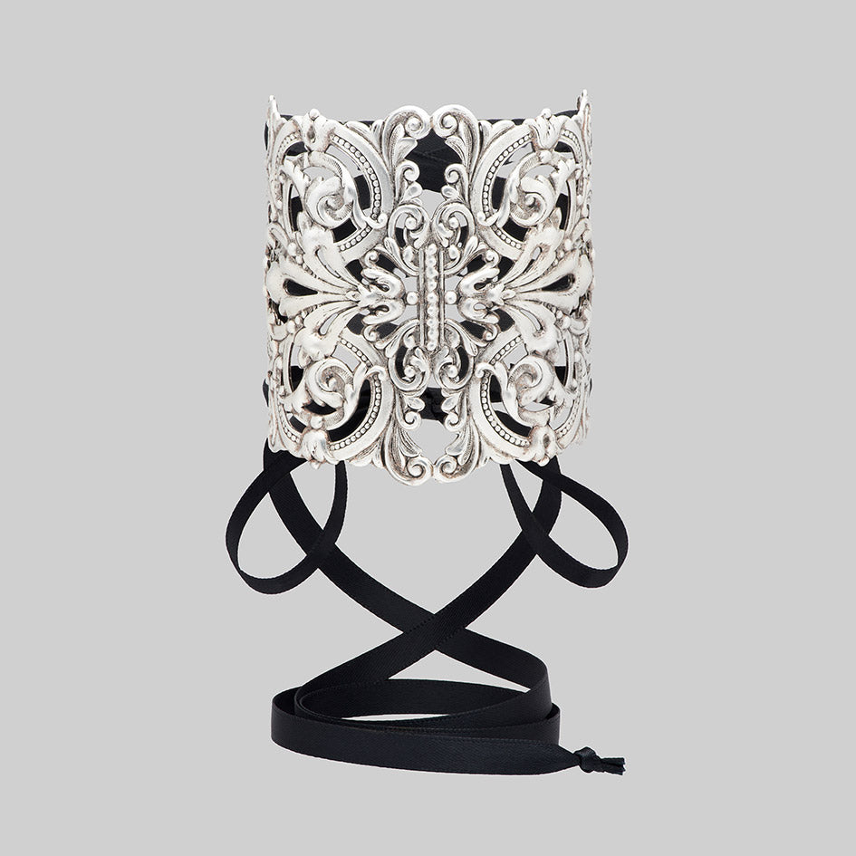 Decorative gothic corset cuff bracelet with intricate design and black lace straps