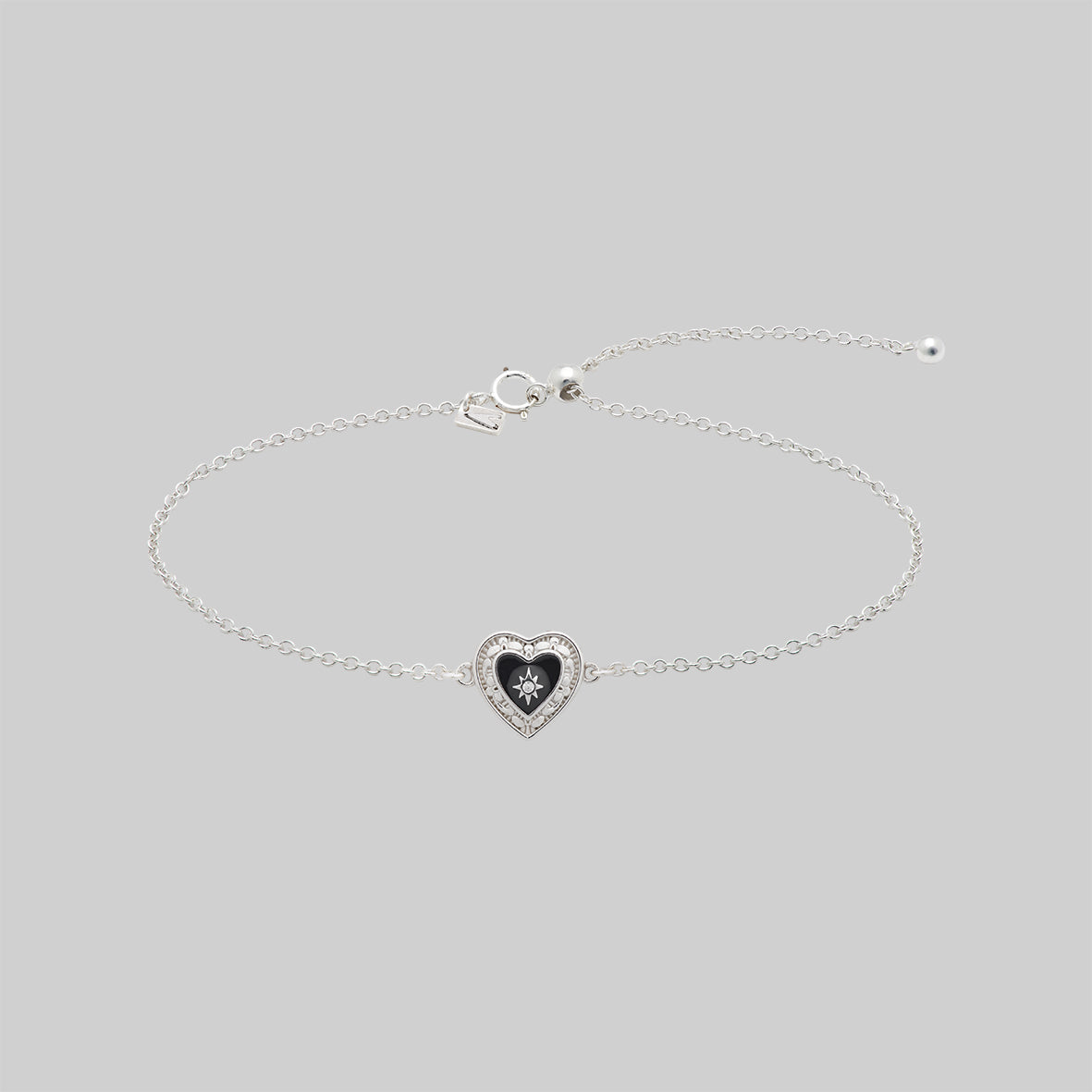 Silver bracelet with a heart-shaped ornate detail on a light gray background