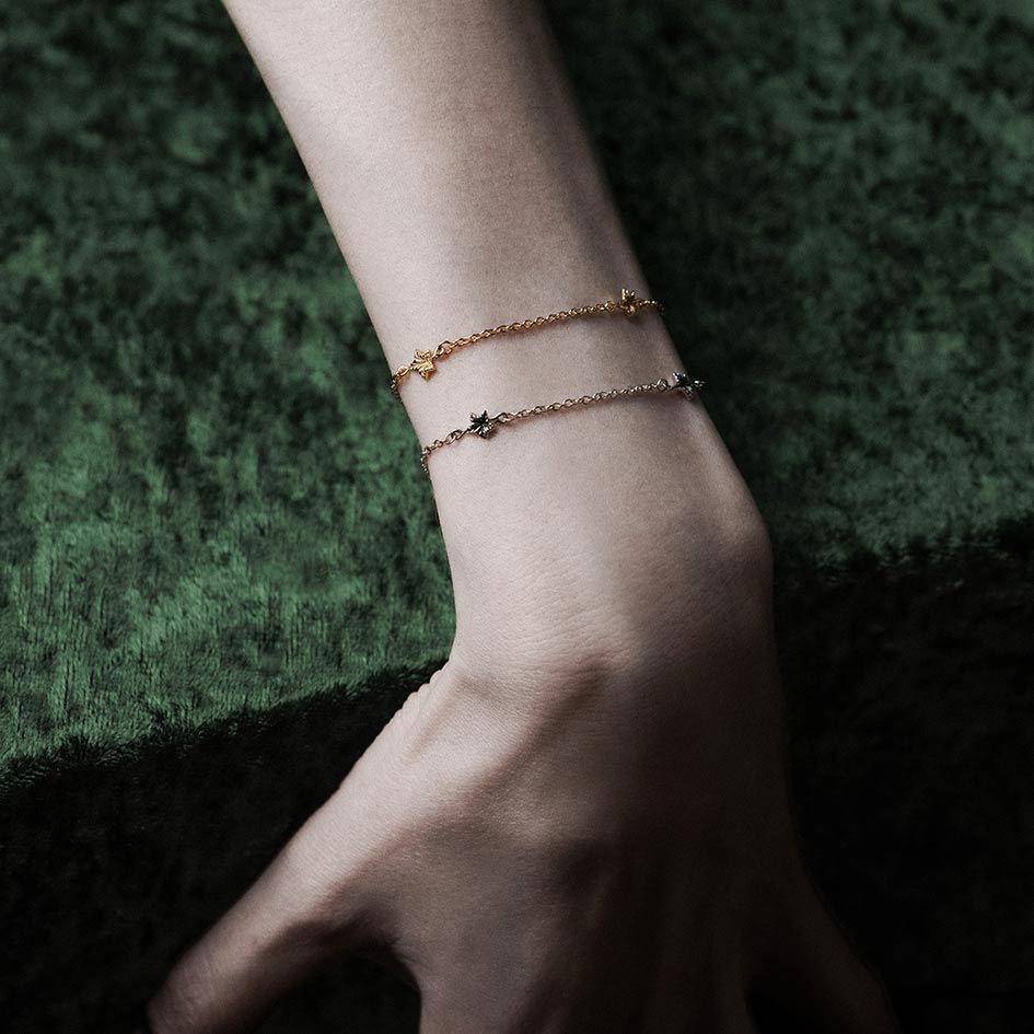Model wearing layered tiny ivy leaf bracelets