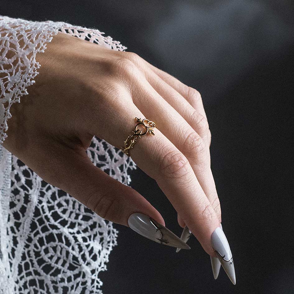 Model wearing Alianor gold plated silver heraldic lily interlace ring on index finger