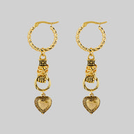 gold hand holding heart earrings