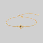 Gold dainty bracelet with a central garnet gemstone and decorative clasp