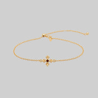 Gold dainty bracelet with a central garnet gemstone and decorative clasp