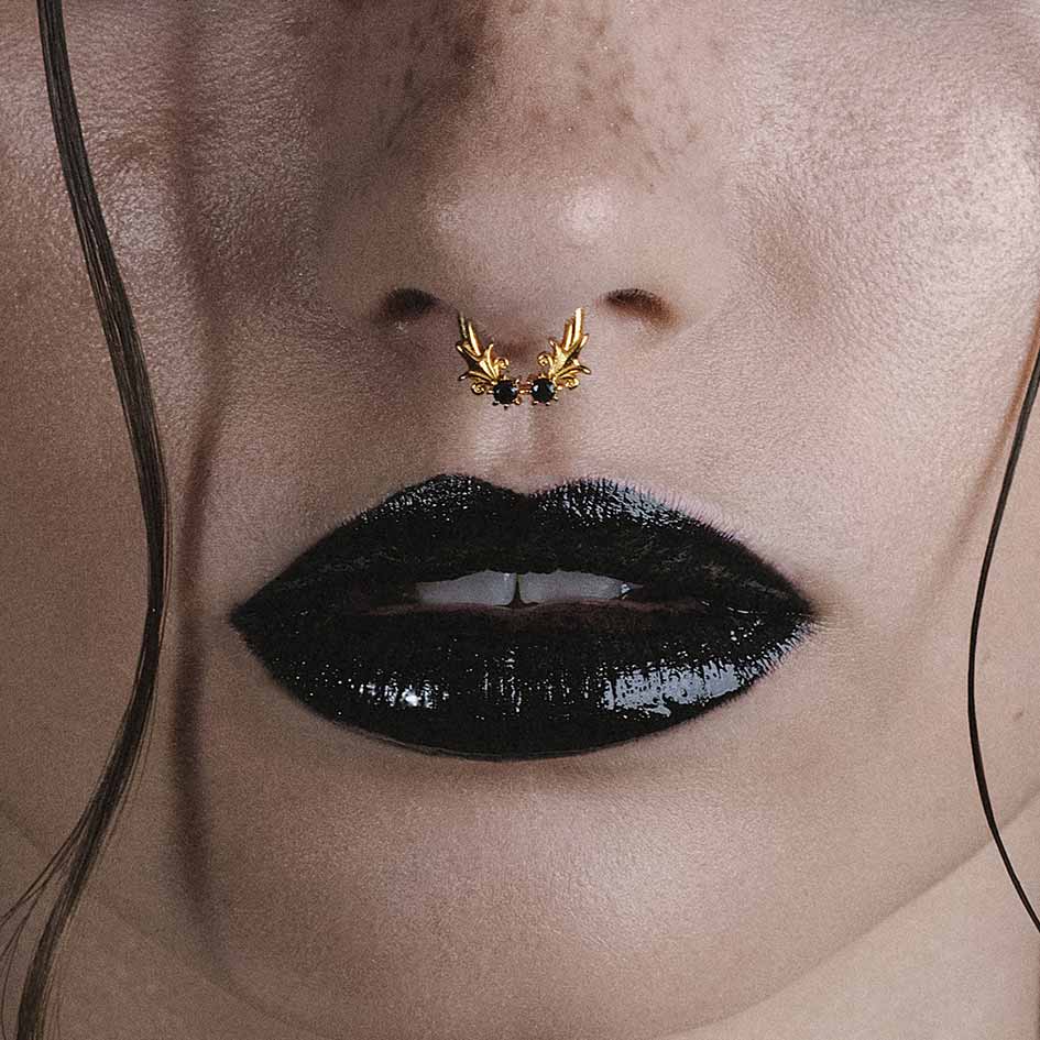 Model wearing Fiora gold heraldic lily black onyx septum clicker ring