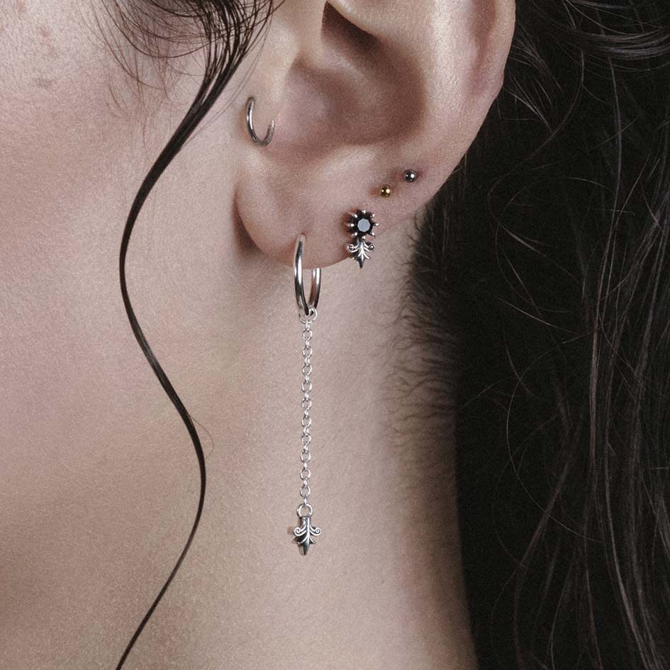Model wearing Fiora silver heraldic lily stud and drop hoop earrings