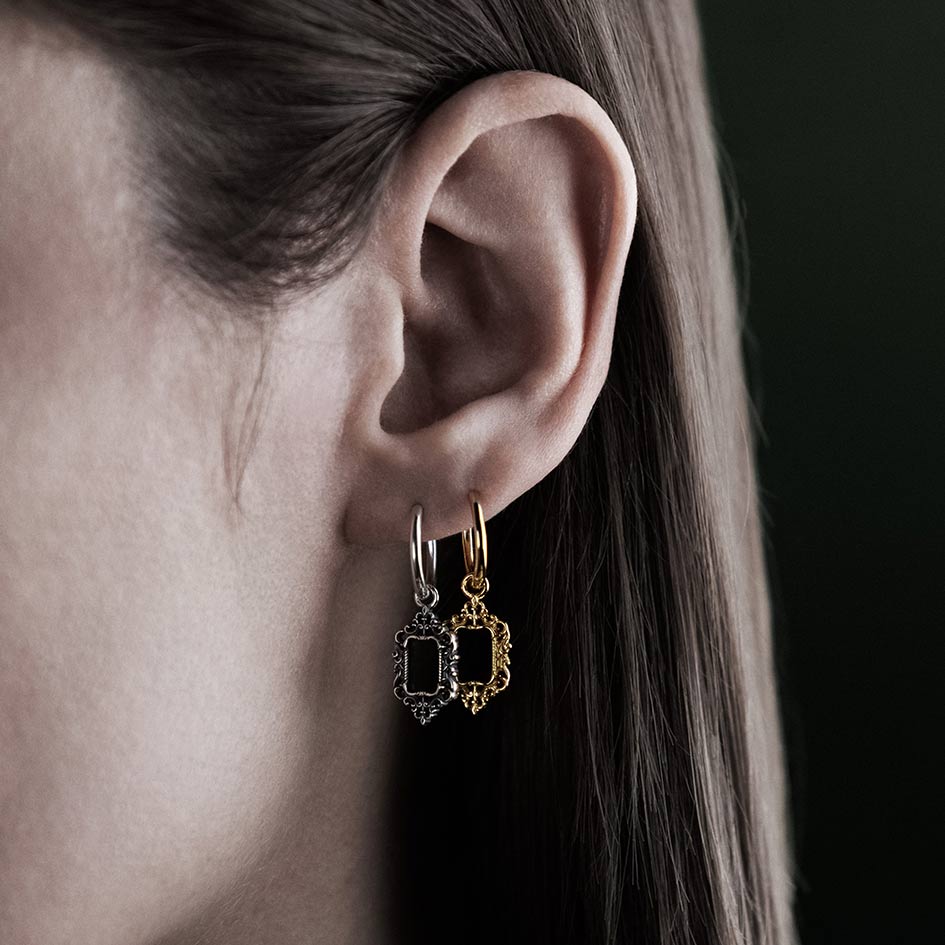Model wearing ornate frame hoop earrings