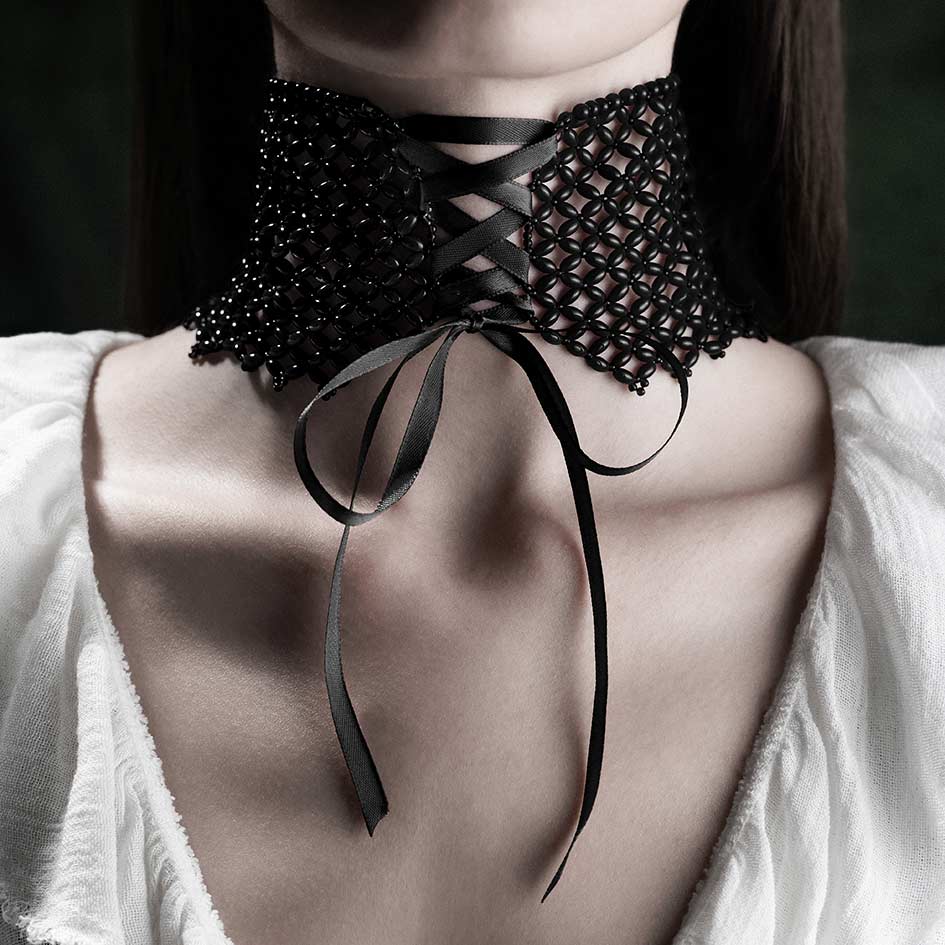 Model wearing black beaded corset choker with ribbon tie