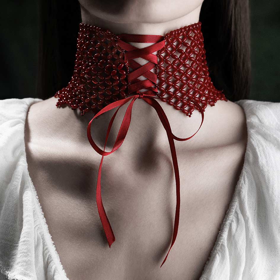 Model wearing red beaded corset choker with ribbon tie