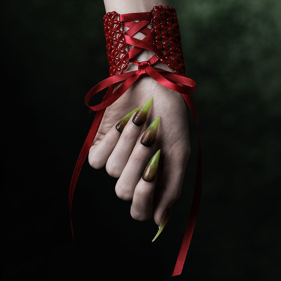 Model wearing red beaded corset cuff, ribbon lacing at back of wrist