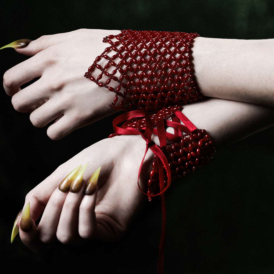 Model wearing red beaded corset cuffs on both wrists