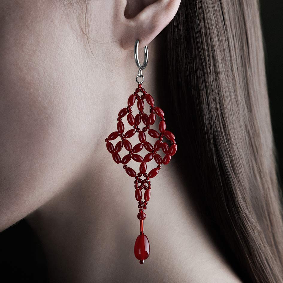 Model wearing red beaded chandelier drop earring on silver hoop