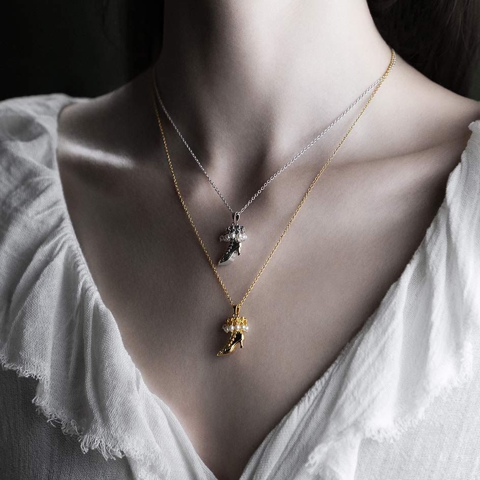 Model wearing layered witches boot pearl necklaces