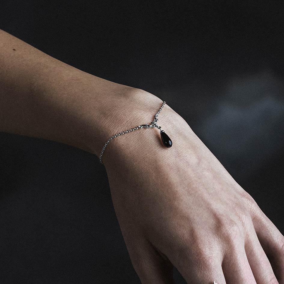 Model wearing Lisette silver heraldic lily black glass droplet bracelet
