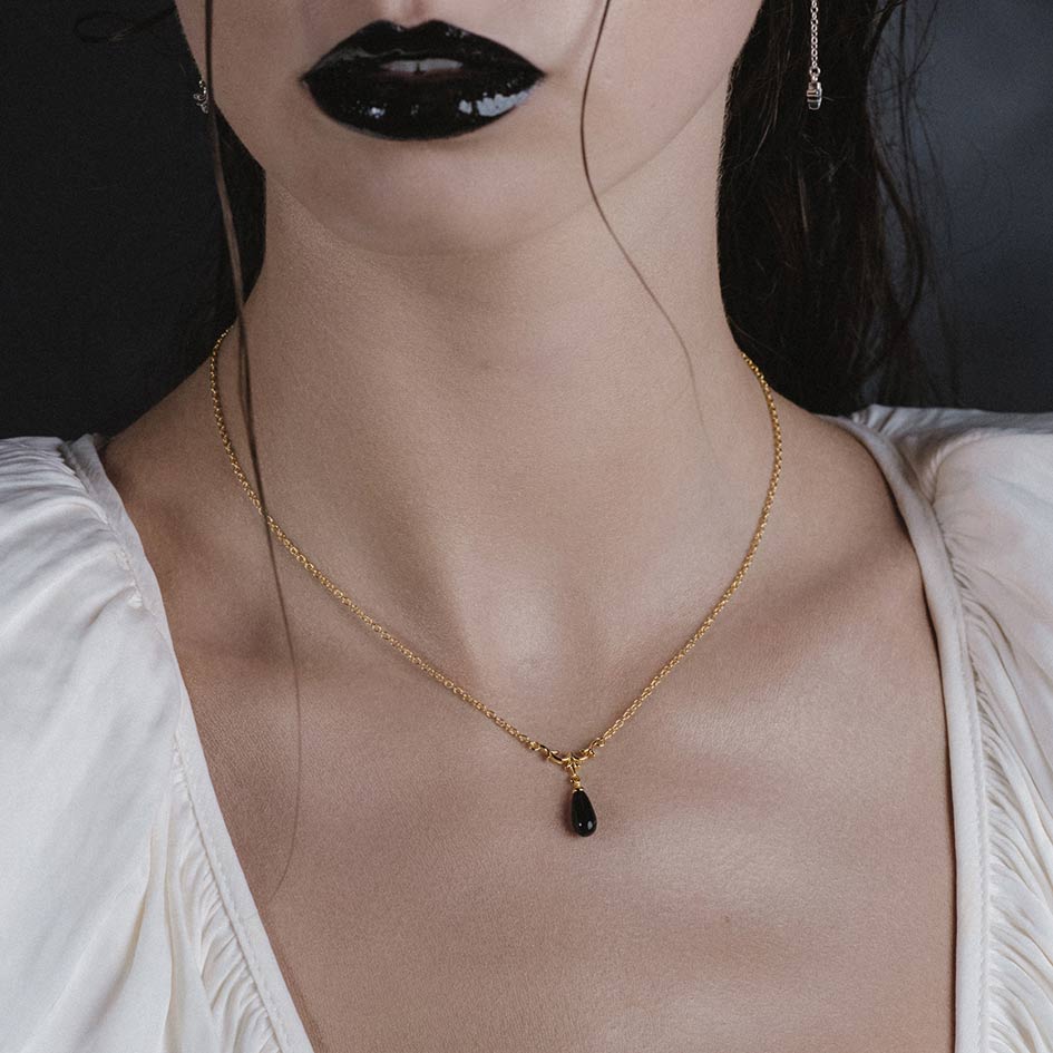 Model wearing Lisette gold heraldic lily black glass droplet necklace