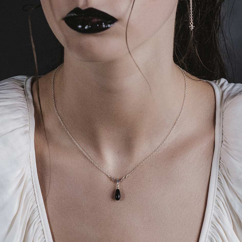 Model wearing Lisette silver heraldic lily black glass droplet necklace