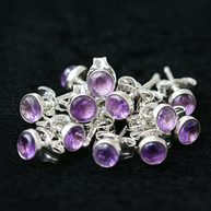 Silver earrings with purple gemstones on a dark background