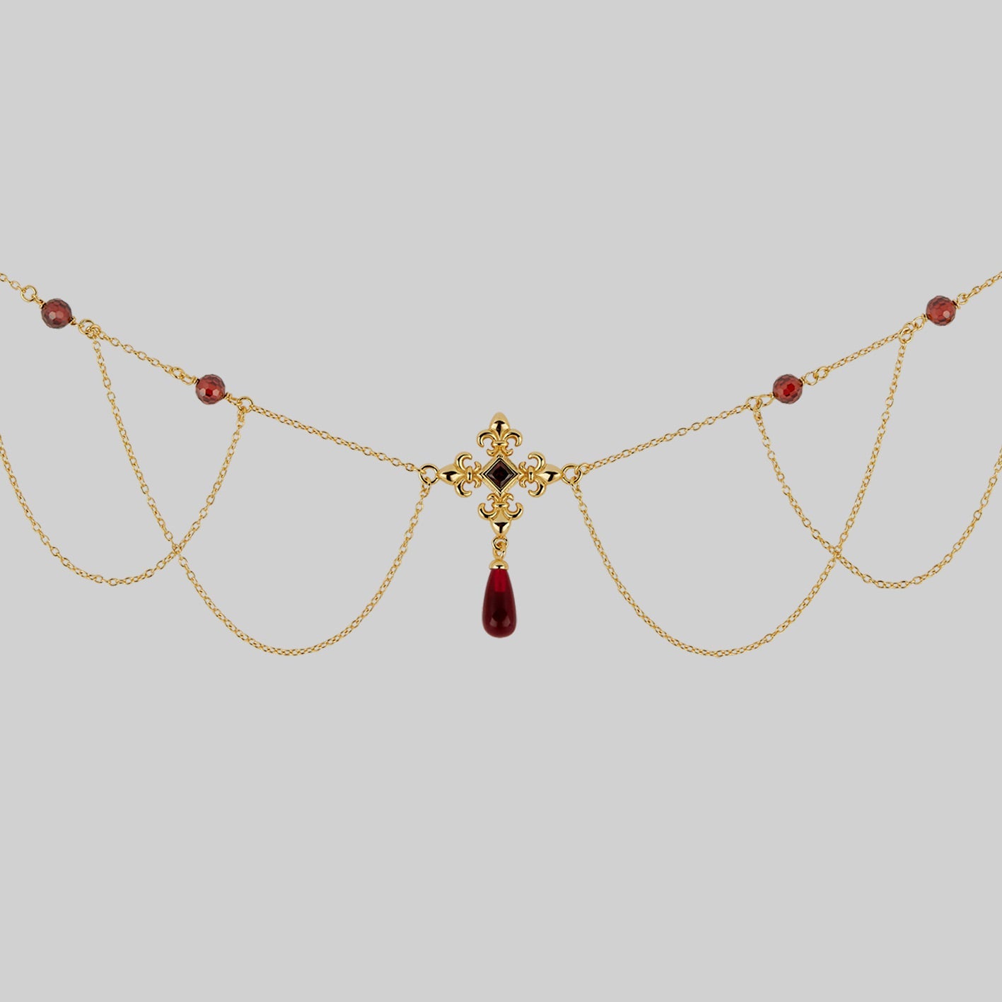 gold draped chain necklace with red gemstones