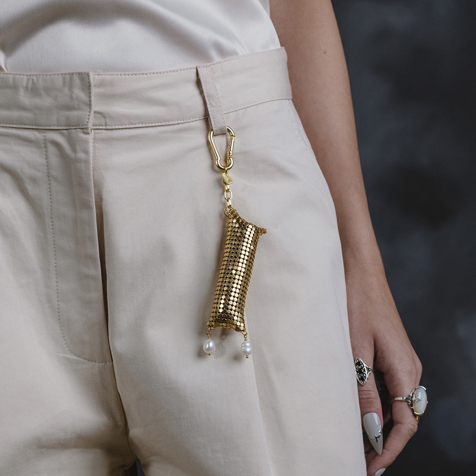 Model wearing Thea gold armoured pearl drop keyring pouch