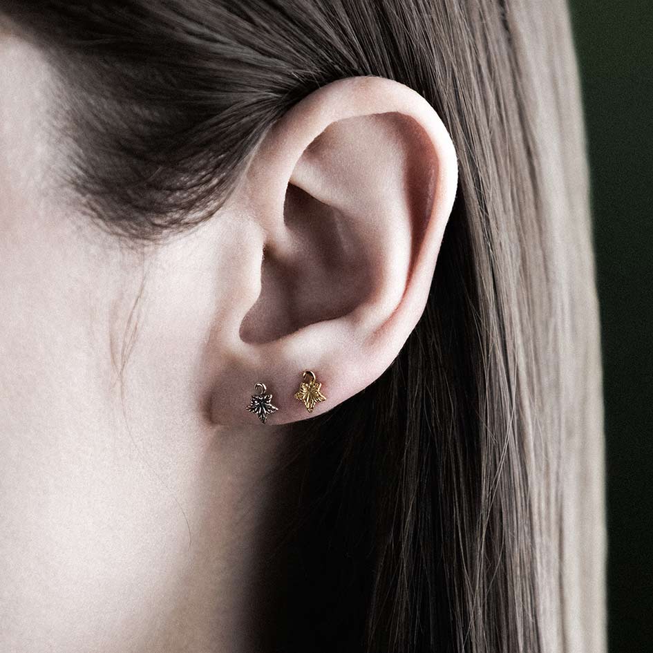 Model wearing gold and silver tiny ivy leaf stud earrings