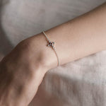 Silver dainty bracelet with a garnet stone on a models wrist