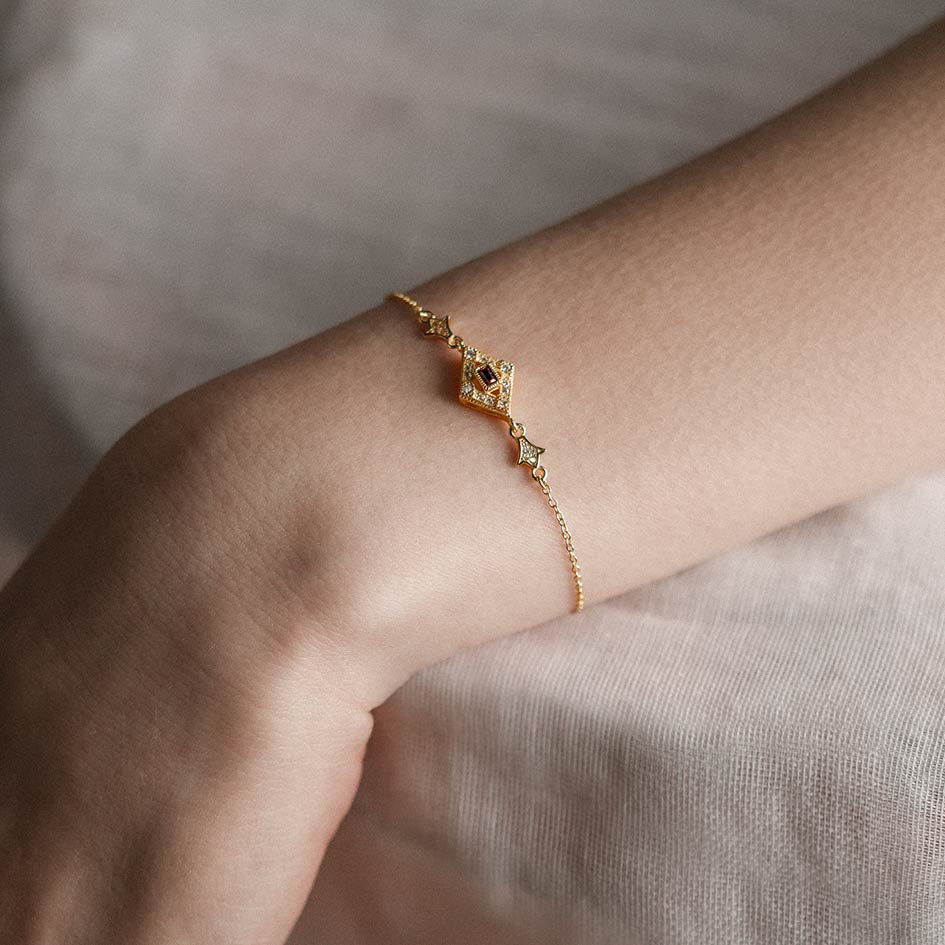 Gold dainty bracelet with a gemstone, worn on a models wrist