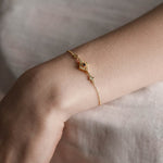 Gold dainty bracelet with a gemstone, worn on a models wrist