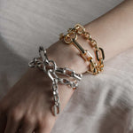 Two chunky chain multi-wrap bracelets, one silver and one gold, worn on a models wrist