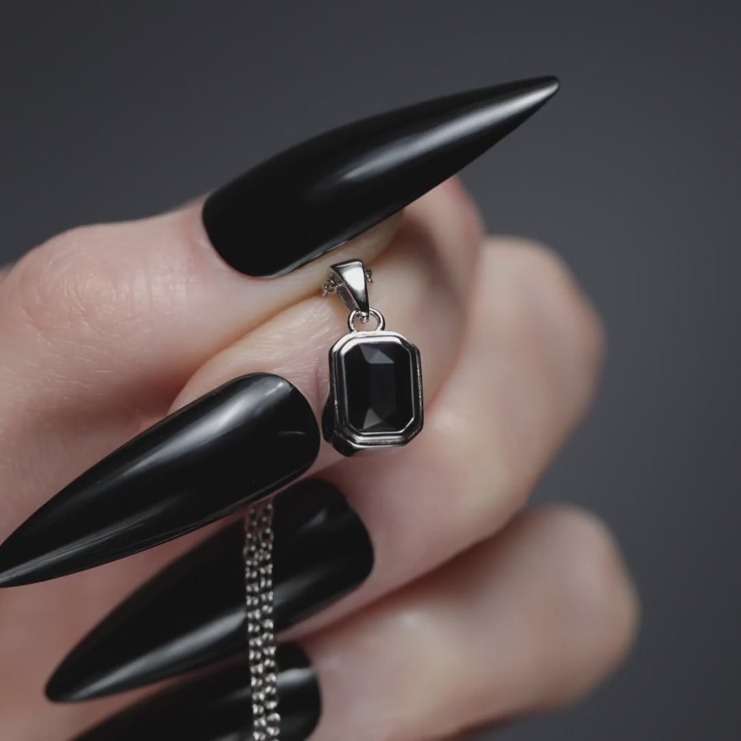 Sterling silver Onyx cremation necklace with the back unscrewed to show ashes being spooned into the hidden chamber