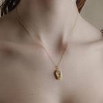 Gold plated necklace with a glass rose coffin pendant on a person's neck