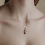 Sterling silver necklace with a detailed glass rose coffin pendant worn on a models neck